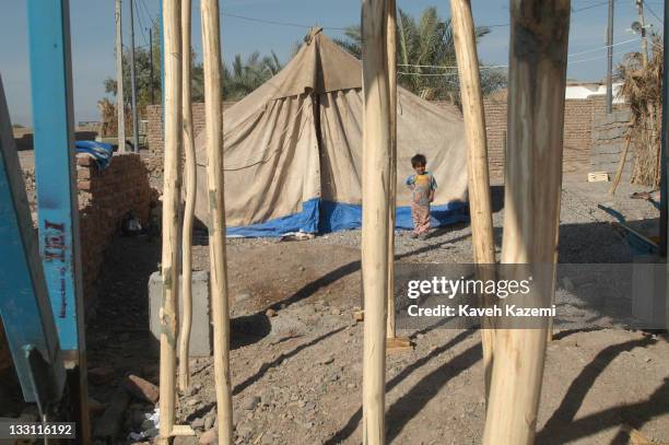 Young girl stands outside a tent where her family has been camping for almost a year after a major earthquake struck the city, Bam, Iran, 6th...