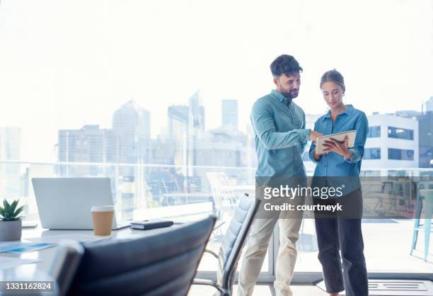 businessman and businesswoman looking at a digital tablet. - business couple showing stockfoto's en -beelden
