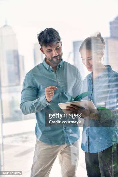 businessman and businesswoman looking at a digital tablet. - repetition office stock pictures, royalty-free photos & images