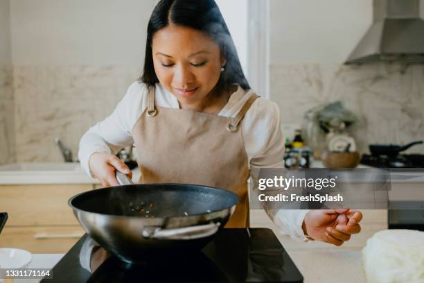 smells delicious! beautiful female filipino cook preparing a tasty meal in a private kitchen - stir frying european stock pictures, royalty-free photos & images