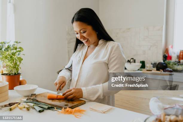 beautiful female filipino cook preparing a tasty meal in a private kitchen - chop stock pictures, royalty-free photos & images