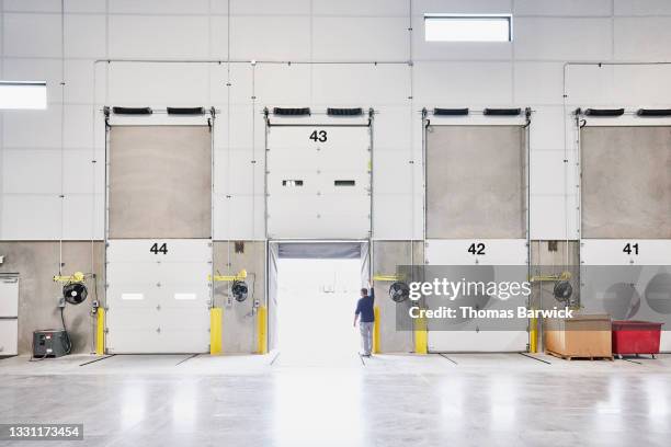 wide shot of worker opening loading door in warehouse - logistica imagens e fotografias de stock