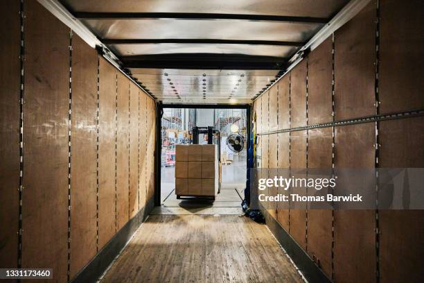 wide view from inside of truck trailer of warehouse worker using forklift to load pallet of goods - loading dock 個照片及圖片檔