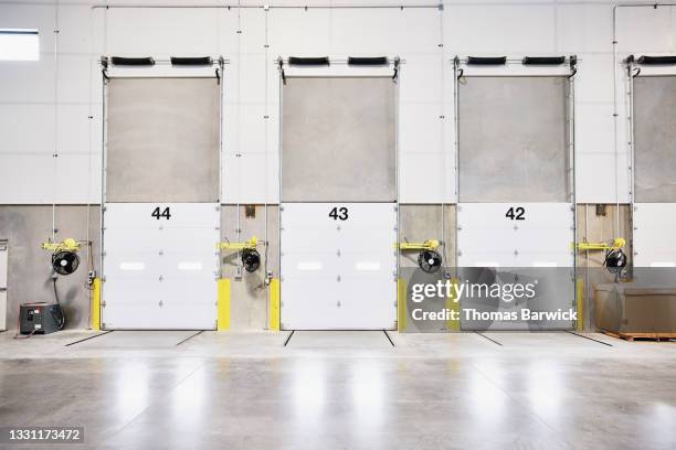 wide shot of closed loading doors in warehouse - shipping ahead of export figures stock-fotos und bilder