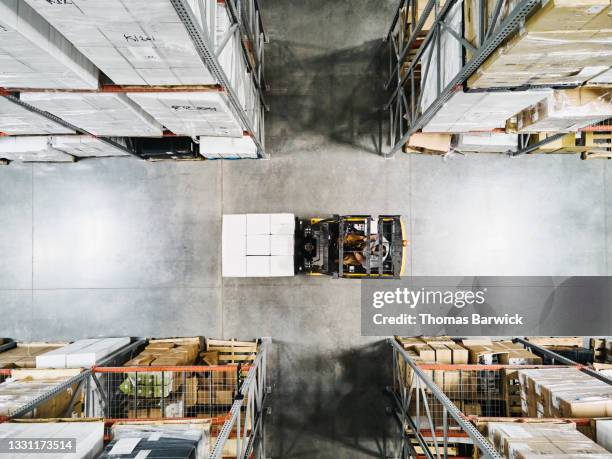 overhead view of warehouse worker moving pallet of goods with forklift in warehouse - pallet industrial equipment fotografías e imágenes de stock