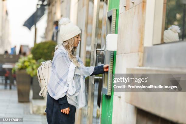 junge frau hebe bargeld vom geldautomaten ab. - bank statement stock-fotos und bilder