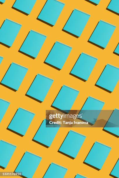 pattern made of blue school notebooks with spiral spring on yellow background, office notepad. minimal composition. copy space, top view, flat lay, copy space - repetition office stock pictures, royalty-free photos & images