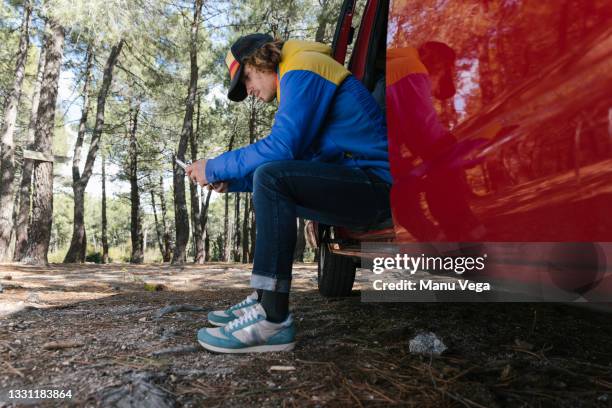 traveler man using a mobile phone during a break from his journey with a camper van. - white van profile stock pictures, royalty-free photos & images