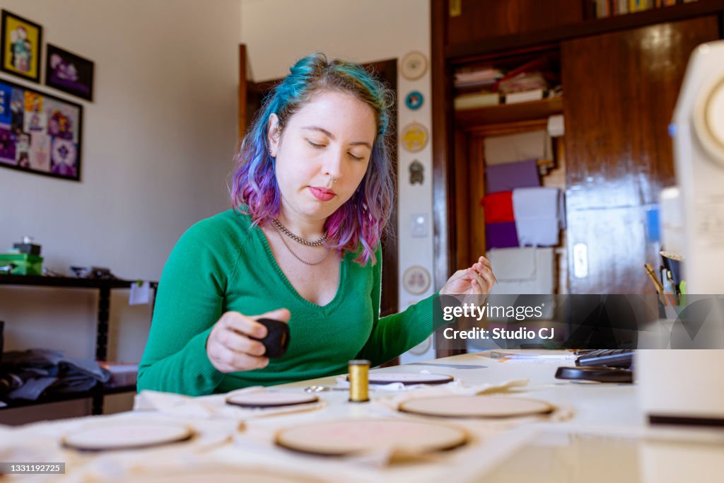 Young artist working on her embroidery hoop design by selecting thread colors