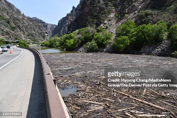 Traffic pass by the Colorado River covered by debris from recent mudslides in Glenwood Springs, Colorado on Wednesday, July 28, 2021.