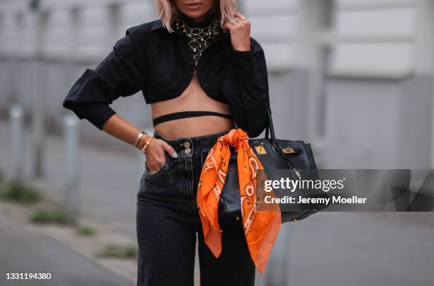 Karin Teigl wearing black Jacquemus top, grey Chanel vintage jeans and scarf and black leather Hermes Birkin bag on July 20, 2021 in Munich, Germany.