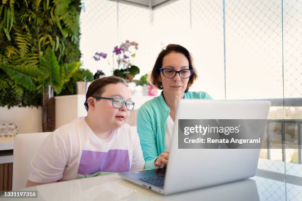 mother and kid with down syndrome at home  in video call with doctor. telemedicine concept. - online doctor stock pictures, royalty-free photos & images