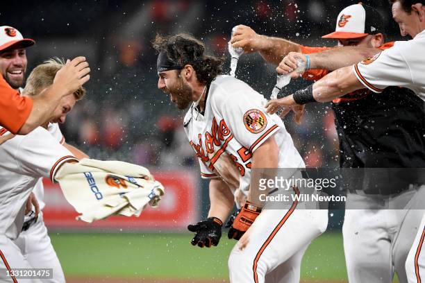 Ryan McKenna of the Baltimore Orioles celebrates with teammates after being walked to drive in the winning run to defeat the Miami Marlins at Oriole...