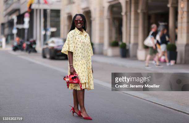 Lois Opoku wearing red Dior heels, red Fendi leather bag, yellow Mads Norgaard mini dress and red Gucci shades on July 25, 2021 in Berlin, Germany.