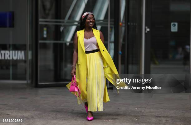 Lois Opoku wearing yellow Karl Lagerfeld coat and midi skirt, Zara top, pink Balenciaga shoes, pink Tory Burch mini bag and Ferragamo bandana on July...