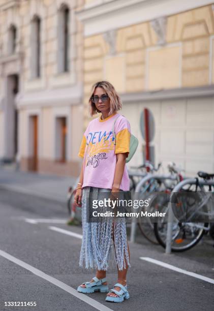 Karin Teigl wearing mint Prada Cleo bag, purple Rhude shades, pink Loewe shirt, blue Jacquemus skirt and blue Ganni sandals on July 20, 2021 in...