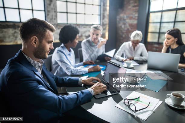 vista de perfil de un hombre de negocios que usa una computadora portátil en una reunión en la oficina. - five people fotografías e imágenes de stock