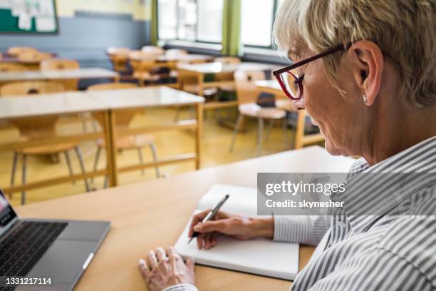 smiling senior teacher taking notes in the classroom. - grading stock pictures, royalty-free photos & images