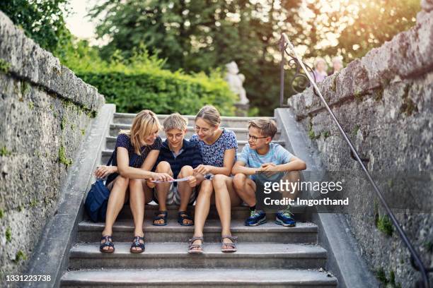 tourist family checking map in mirabellgarten park, salzburg, austria - family city break stock pictures, royalty-free photos & images