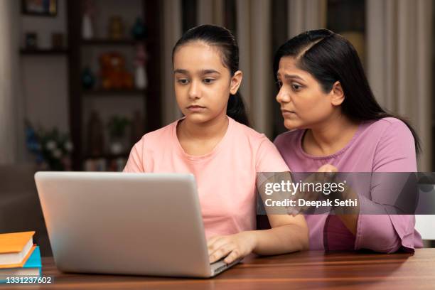 shot of a mother and daughter using laptop at home - class argument stockfoto's en -beelden