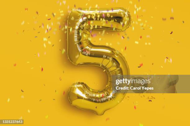 number 5  foil golden ballon in gold background with confetti - the number 5 stock pictures, royalty-free photos & images