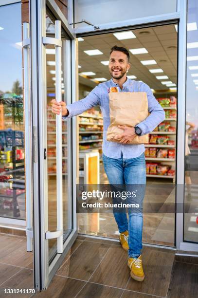 customer walking out of a supermarket very happy carrying her groceries in a paper bag - leaving store stock pictures, royalty-free photos & images