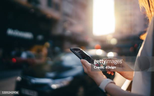 cropped shot of young woman reading financial trading data on smartphone in downtown city street on the go, with busy traffic and urban city scene in background - car display background stock-fotos und bilder