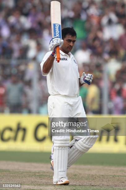 Mahendra Singh Dhoni of India raises his bat after scoring a century during the second day of second Test Match between India and West Indies at Eden...