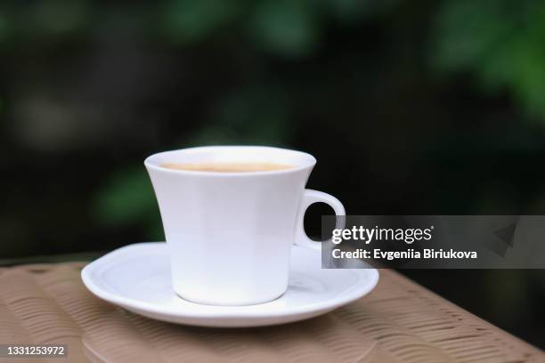 white cup with coffee and white saucer on a wooden table with greens on the background - broken mug stock pictures, royalty-free photos & images