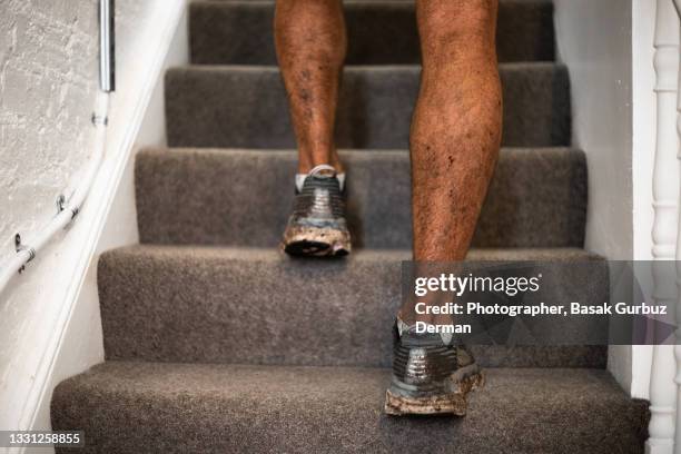 close-up of a man entering the house with his dirty shoes after training - running shoes close up stock-fotos und bilder