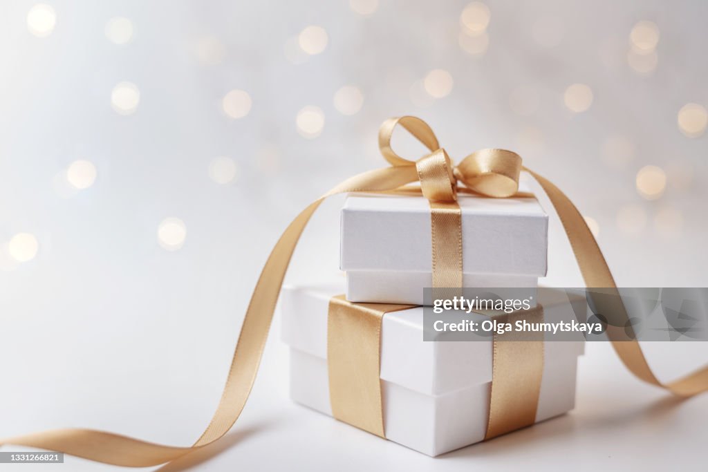 Two white gift box with gold ribbon on bokeh background
