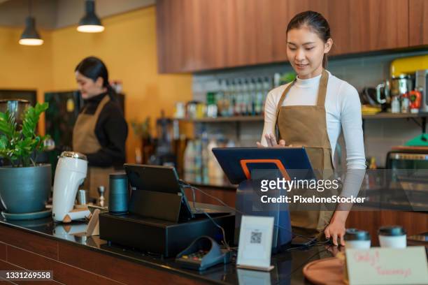 women cashier behind the counter fill customer orders in the coffee shop and cafe - キャッシュレジスター ストックフォトと画像