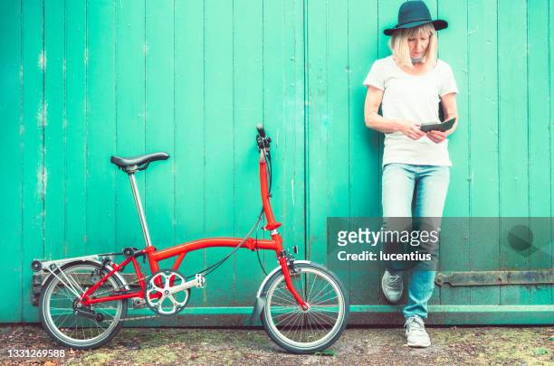 woman using her mobile phone while out cycling. - opvouwbaar stockfoto's en -beelden