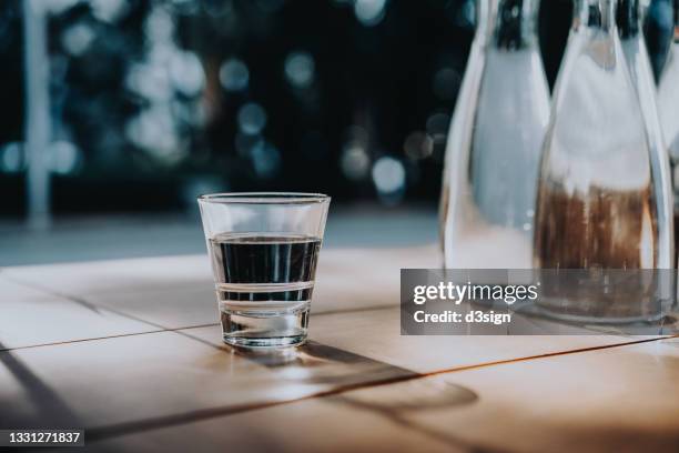 a glass of water served on table next to bottles of water in an outdoor restaurant against beautiful sunlight - 3 d glasses foto e immagini stock