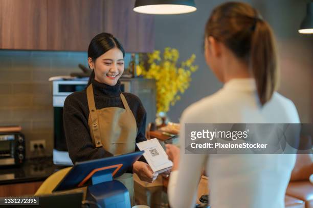 Women cashier received customer payment via scan QR code in the Coffee Shop.
