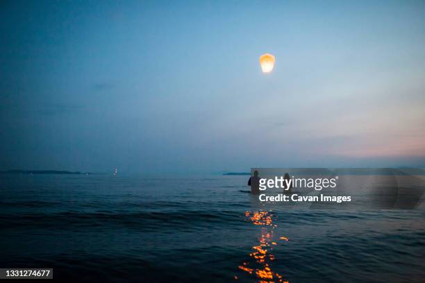 two people in release paper lantern from lake - burlington vermont fotografías e imágenes de stock