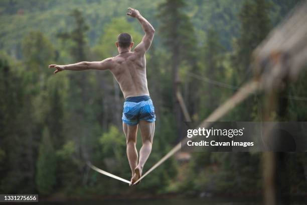 male slackliner walking a long slackline - slackline stock-fotos und bilder