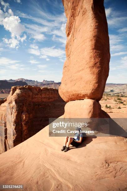 a female hiker rests against delicate arch in arches national park, utah. - delicate arch stock pictures, royalty-free photos & images