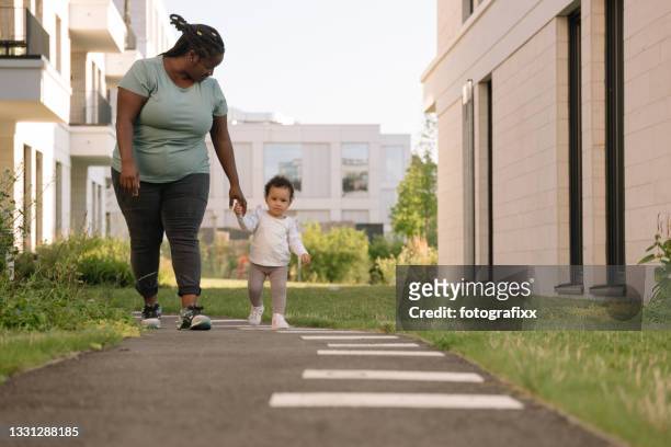 cute baby girl made first steps at mother's hand - townhouse stock pictures, royalty-free photos & images