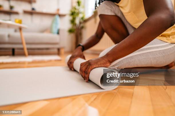 woman rolling her mat after her home workout - mat stock pictures, royalty-free photos & images