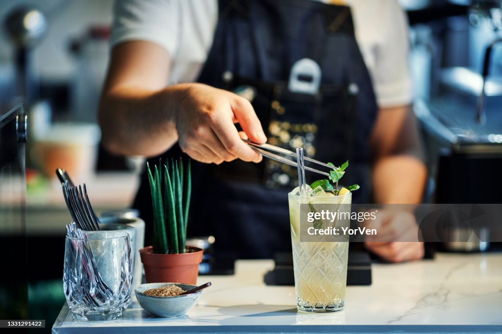 Barman mélangeant cocktail avec de la menthe