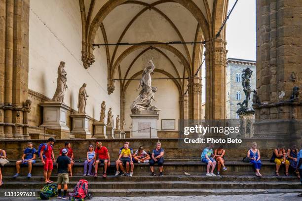 dozens of tourists rest under the loggia dei lanzi in piazza della signoria in the heart of florence in tuscany - piazza della signoria stockfoto's en -beelden