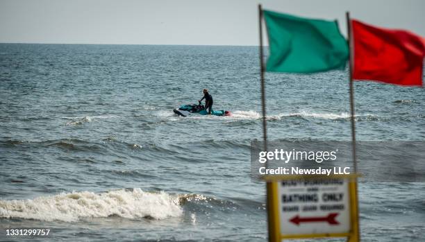 Town of Hempstead lifeguard patrols the waters on a jet ski for sharks in the Atlantic Ocean off Lido West Beach in Lido Beach, New York, on July 28,...