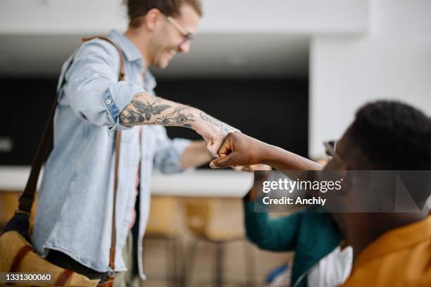 los estudiantes universitarios se saludan durante un encuentro - fist bump fotografías e imágenes de stock