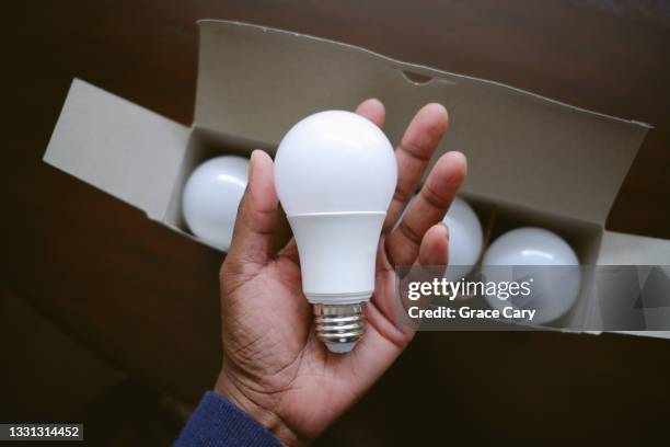 woman holds led light bulb - diodo emisor de luz fotografías e imágenes de stock