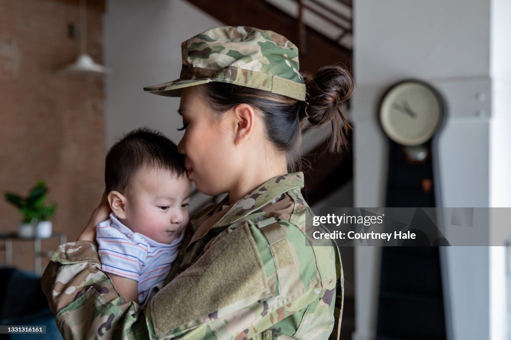Young female soldier has bonding moment with newborn son before reporting for military duty