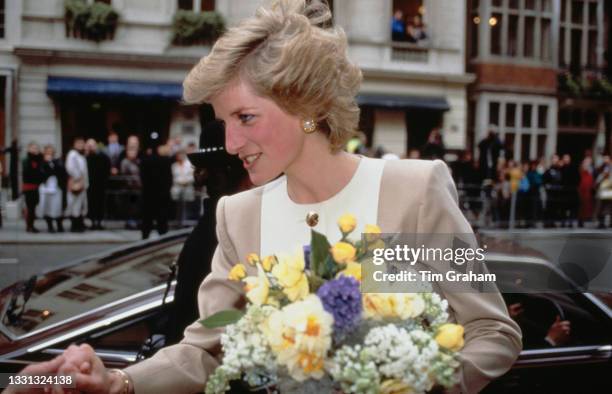 British Royal Diana, Princess of Wales , wearing a beige-and-white suit by Catherine Walker, carrying flowers as she leaves King Edward VII's...