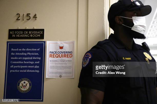 Capitol Police officer wears a mask as signs regarding the new facial mask mandate are posted outside a hearing room of the Subcommittee on Civil...
