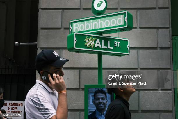 People wait in line for t-shirts at a pop-up kiosk for the online brokerage Robinhood along Wall Street after the company went public with an IPO...
