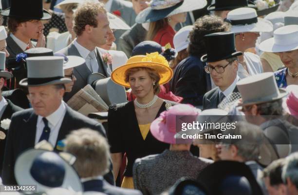 Danish member of the British Royal Family Birgitte, Duchess of Gloucester, wearing a yellow wide brim hat, among unspecified racegoers attend the...